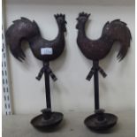 A pair of rustic rivetted tinplate and copper candle sconces, fashioned as cockerels, on saucer