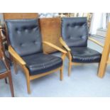 A pair of 1970s/1980s stained beech framed armchairs with black faux hide cushioned backs and seats,