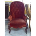 A late Victorian walnut framed salon chair with a red fabric upholstered back and seat, raised on