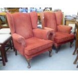 A pair of modern red fabric upholstered wingback armchairs, raised on cabriole legs