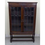 An Art Nouveau oak bookcase with a pair of glazed doors, raised on barleytwist supports, united by