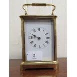 A 20thC lacquered brass cased carriage clock with bevelled glass panels and a folding top handle, on