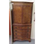 A mid 20thC walnut veneered and crossbanded, serpentine front tallboy style, two part cupboard,