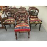 A harlequin set of seven Victorian mahogany framed and carved balloon back dining chairs, later re-