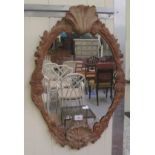 An early 20thC mirror, the shaped plate set in a shell and foliate carved pine frame  26" x 18"