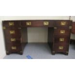 A 19thC design military style mahogany, nine drawer, twin pedestal desk with brass fittings, the top