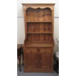 A modern waxed pine two-part dresser, comprising open plate display shelves, over a pair of