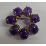 A yellow metal circular brooch  stamped 585 and claw set with seven amethyst coloured stones