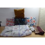 A quilt, other textiles and variously patterned scatter cushions