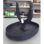 A 19thC black painted cast iron boot scraper, on an oval tray base