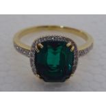 A gold coloured metal claw set, simulated emerald and diamond ring