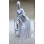 A Lladro porcelain figure, a lady wearing a long gown, standing bedside a chair  model no.1276  19"h