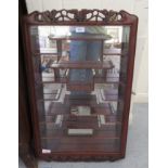 A modern Japanese rosewood netsuke cabinet with a glazed door, enclosing tiered shelves  32"h  20"w