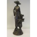 A 20thC cast and burnished bronze standing figure, a fashionable young woman beside a flower vase,