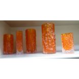 Whitefriars tangerine coloured glass, comprising a pair and one smaller bark effect cylindrical