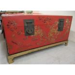 A modern Chinese red lacquered and overpainted storage trunk with straight sides, ornately cast