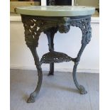 An early 20thC dark green painted, cast iron pub table with a wooden top, the base featuring masks