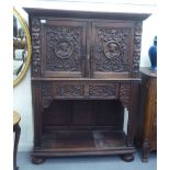 An early 20thC Flemish inspired carved oak court cupboard with a pair of doors, over a central