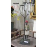 A 20thC lamp, fashioned as a boy wearing a red turban, standing barefoot with a pot and five glass