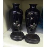 A pair of Japanese cloisonné baluster vases, decorated with flora and songbirds, on a black