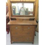 A 1930s Arts & Crafts inspired oak dressing table, the bevelled mirror pivoting on square horns,