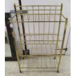 A modern lacquered, square section and tubular brass railed, three tier stand, on casters  41"h