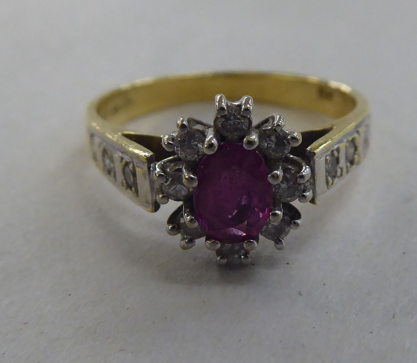 An 18ct gold cluster ring, set with a central ruby, surrounded and flanked by diamonds