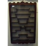 A modern Japanese rosewood netsuke cabinet, having a glazed door, enclosing a tiered interior  33"h