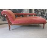 A late Victorian walnut framed chaise longue, upholstered in a red fabric, raised on turned legs