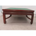 A Chinese rosewood coffee table with a baize top, raised on block legs  17"h  34"w