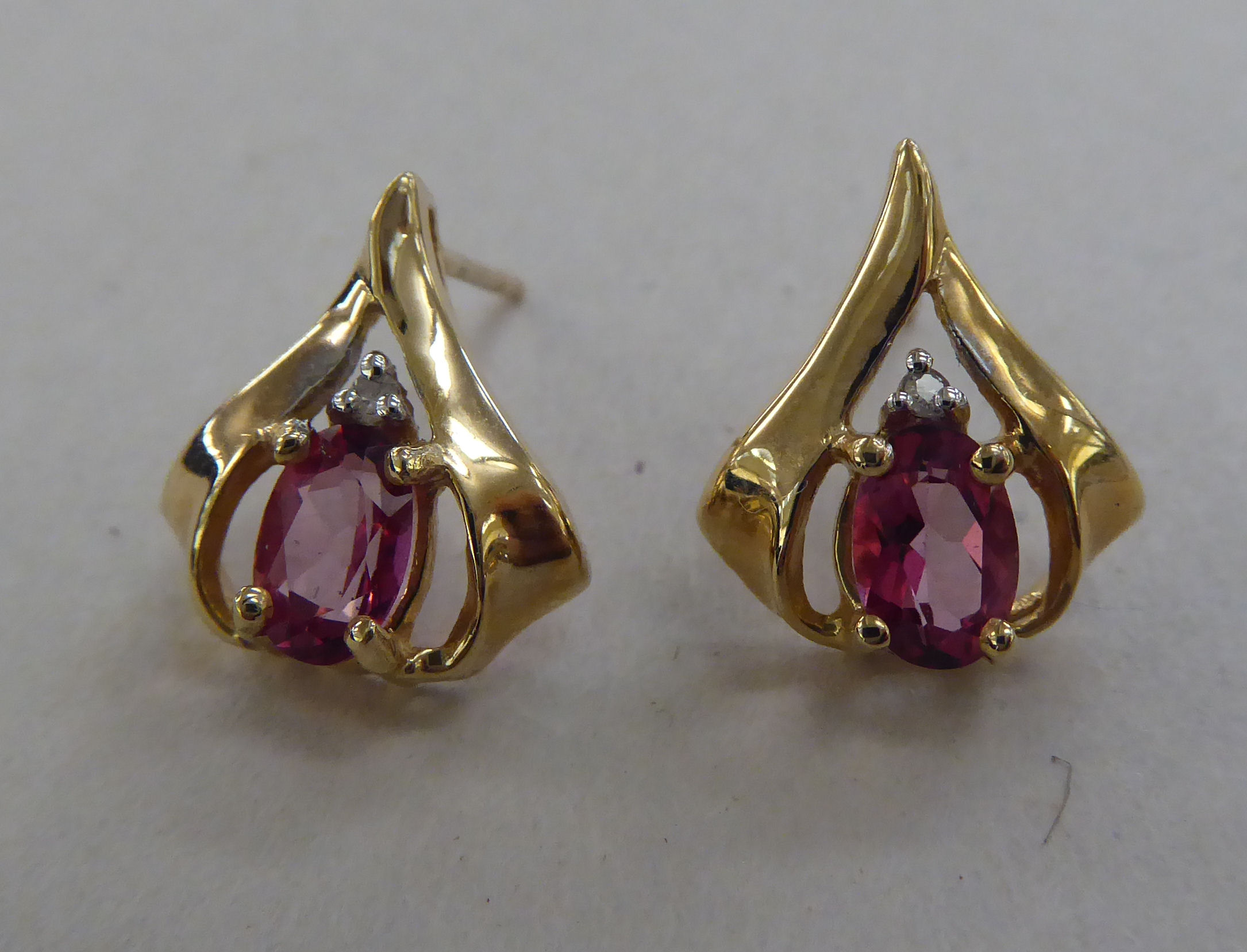 A pair of 10k gold earrings, each set with a pink stone and a diamond