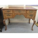 A late 19th/early 20thC crossbanded mahogany and walnut, five drawer kneehole desk, raised on