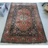 A Persian woollen and silk rug, decorated with dense flora, on a peach, blue and green ground  56" x