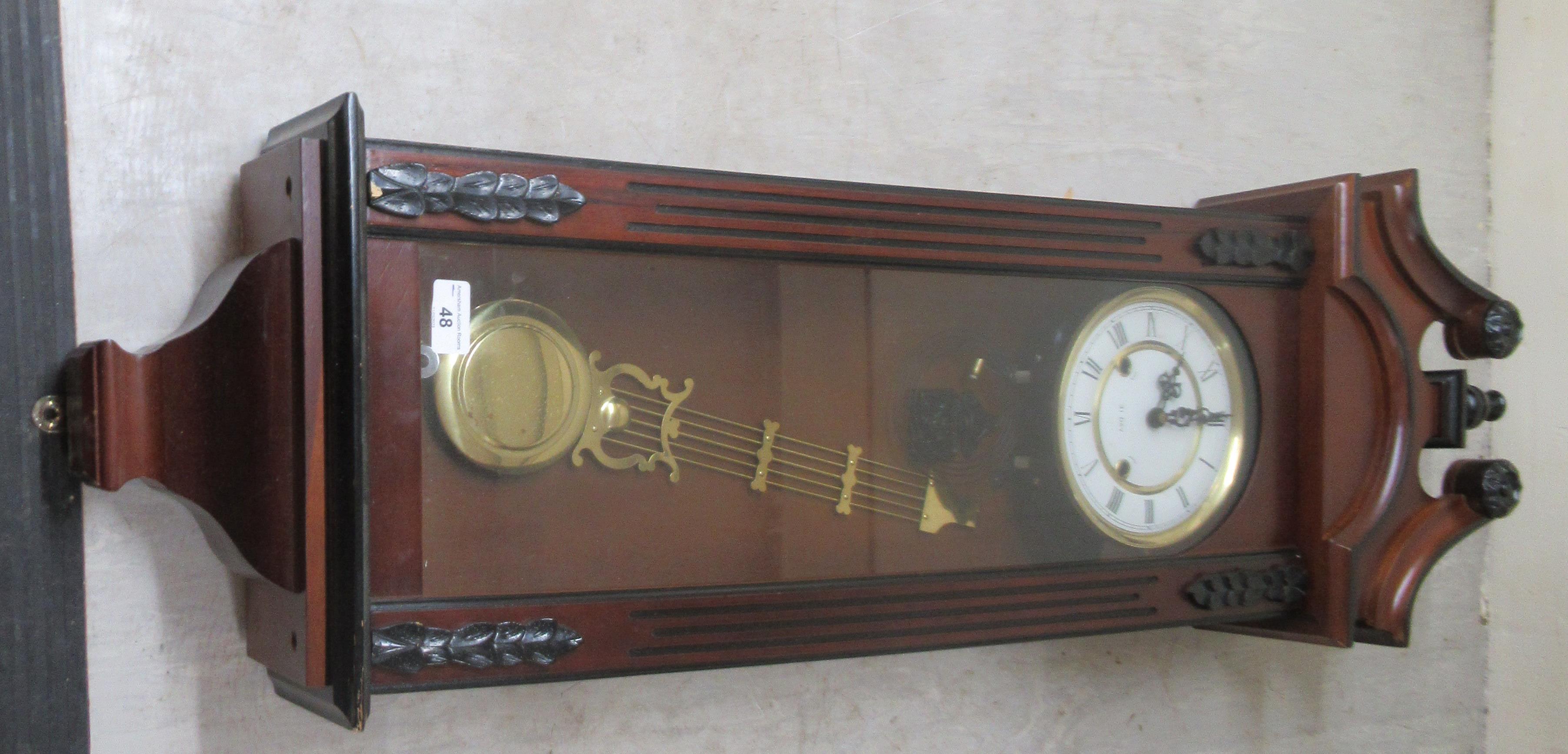 A modern mahogany cased and glazed wall clock; the 31 day movement faced by a Roman dial  43"h