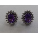 A pair of 9ct gold cluster earrings, each set with a central amethyst, surrounded by diamonds