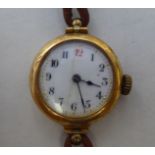 A ladies 15ct gold cased wristwatch, faced by an Arabic dial, on a brown hide strap