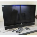 A Loewe Individual 40" television, on a rotatable stainless steel stand with two remote controls