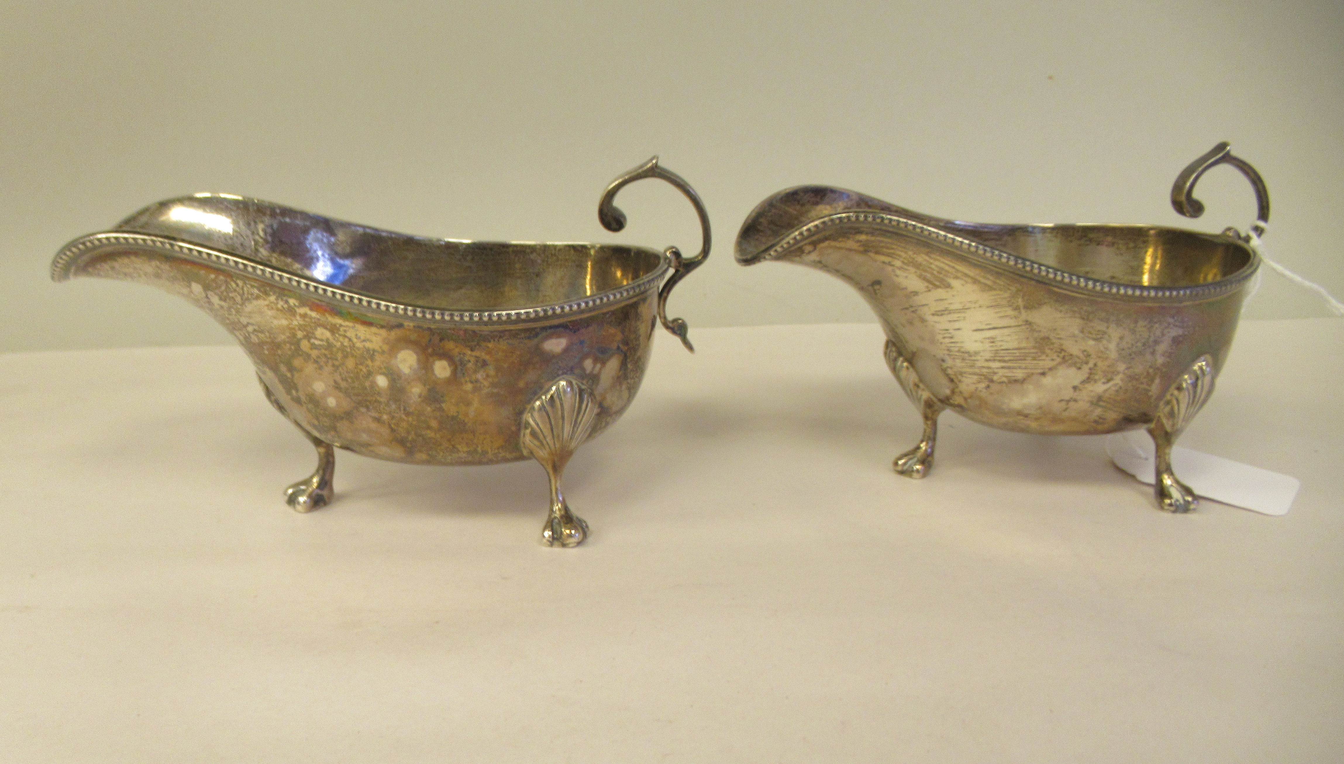 A pair of silver sauce boats with bead borders and C-scrolled handles, elevated on cast paw feet