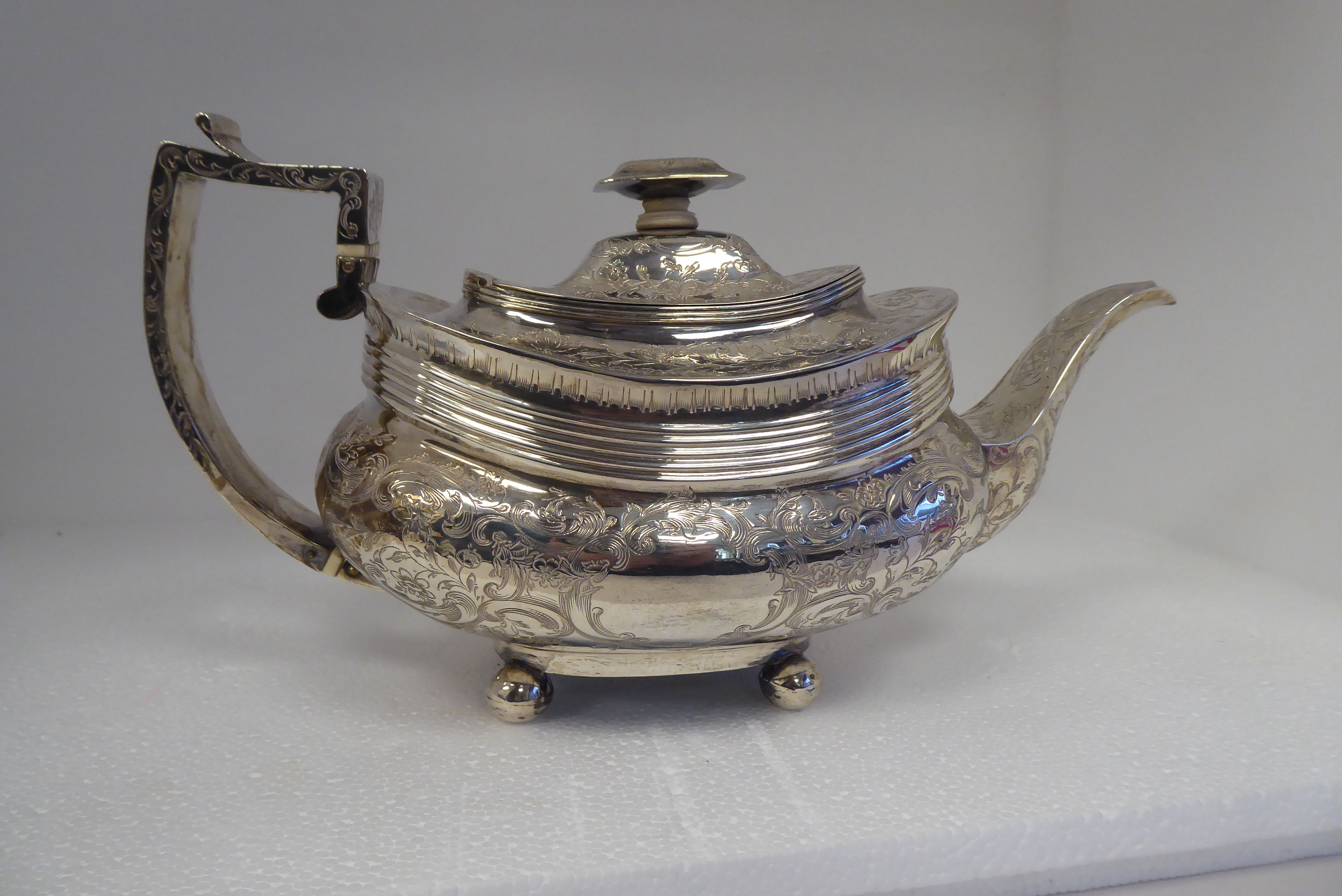 A George IV silver teapot of oval, ogee form with a swept spout and angular handle, flush fitting