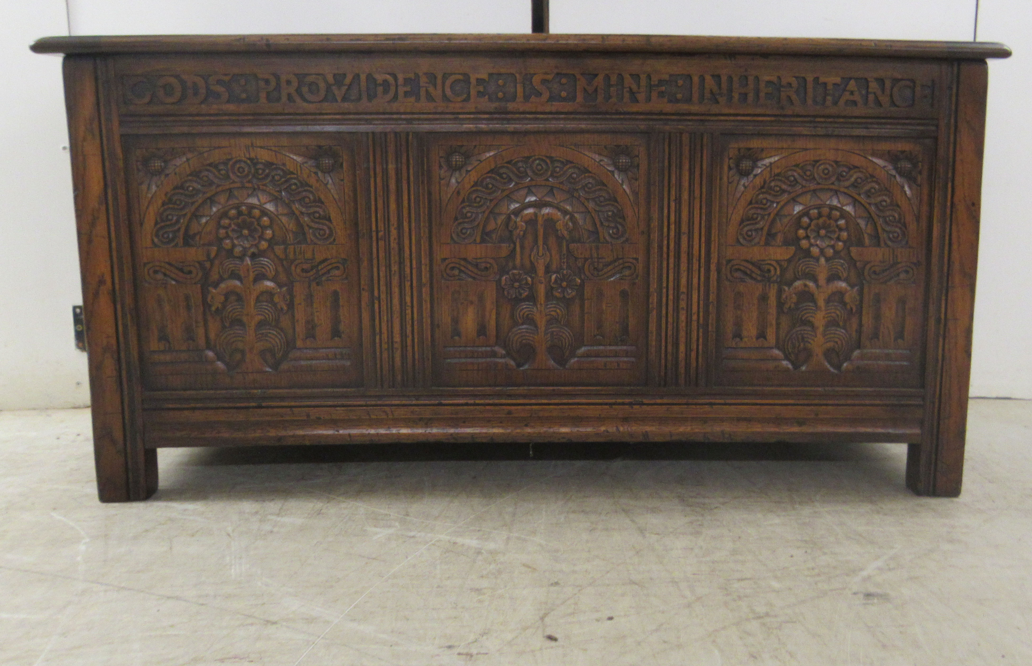 A Brights of Nettlebed period style, tri-panelled oak chest, the front with relief carved