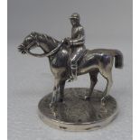 A miniature white metal model, a mounted horserace jockey, on a floral engraved circular base  2.