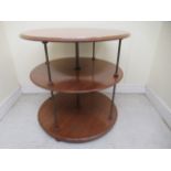 A 19thC mahogany three tier display table, elevated on tubular brass supports and rotating on a