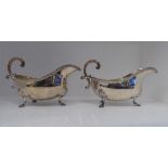 A pair of silver sauce boats with gadrooned rims and hollow double C-scrolled handles, elevated on