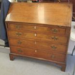 A George III oak bureau with a fall flap, over four long graduated drawers, raised on bracket