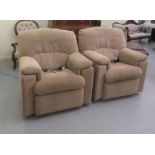 A pair of modern electrically operated reclining enclosed armchairs, upholstered in an oatmeal