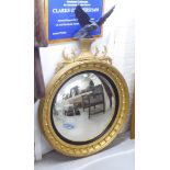 A reproduction of a Regency gilded convex mirror, surmounted by a bird of prey and foliate ornament