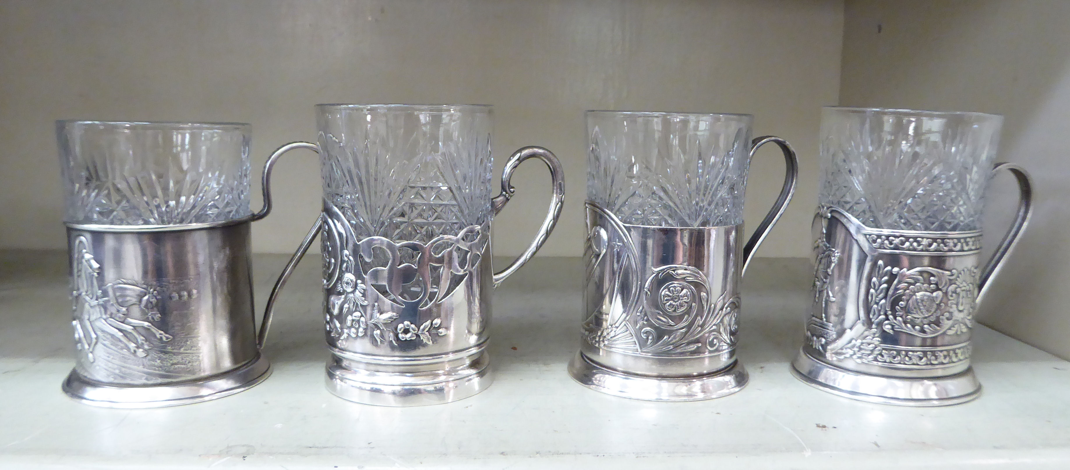 Four Russian moulded glass breakers, in matched white metal frames with loop handles