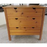 A modern honey coloured and panelled pine three drawer dressing chest with cut-out handles, raised