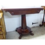An early Victorian mahogany tea table, the rotating foldover top raised on a turned pedestal disc