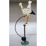 A novelty painted iron counter balance toy, featuring a child riding a stork, pivoting on a weighted